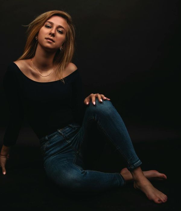 Woman in a calm, balanced pose against a dark background.